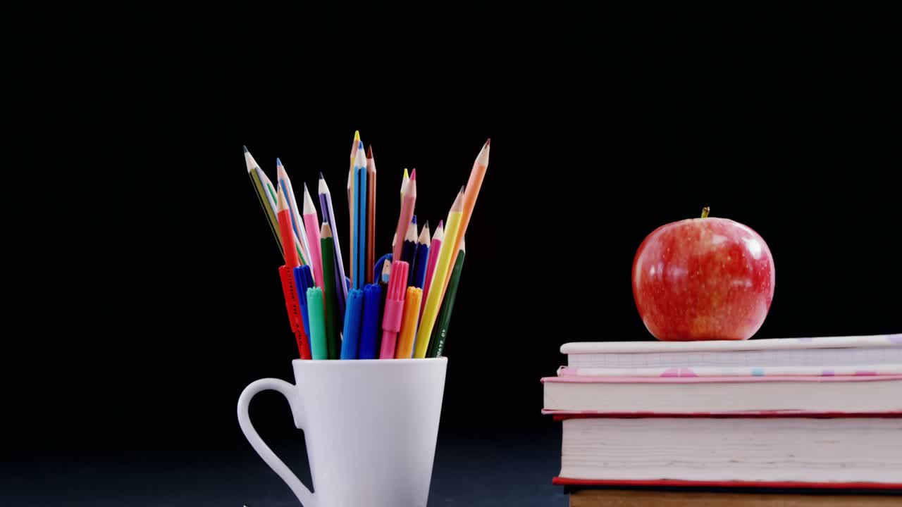 Apple on book stack with school supplies