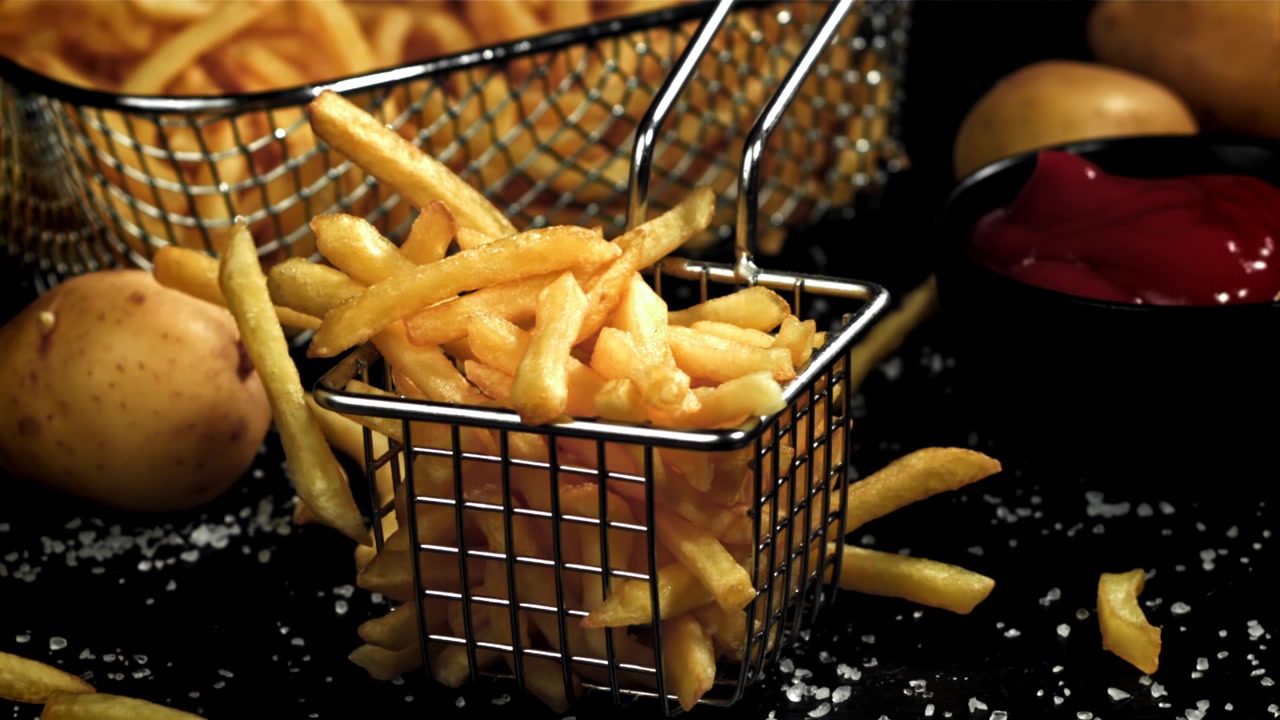 Batatas Fritas Douradas Caindo em uma Cesta de Metal com Ketchup e Sal
