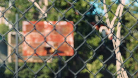 pull focus shot of basketball hoop through fencing