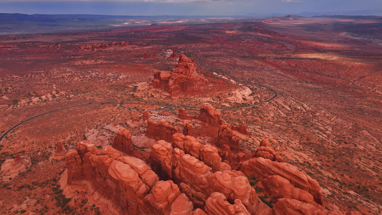 Inmenso paisaje desértico con caprichosas rocas de color rojo. La carretera se acerca cruzando el paisaje del Parque Nacional Arches en Utah, EE. UU.