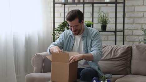 millennial man opening parcel box feels satisfied by delivered goods