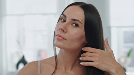 portrait serious woman brushing hair in bathroom. girl combing silky chevelure