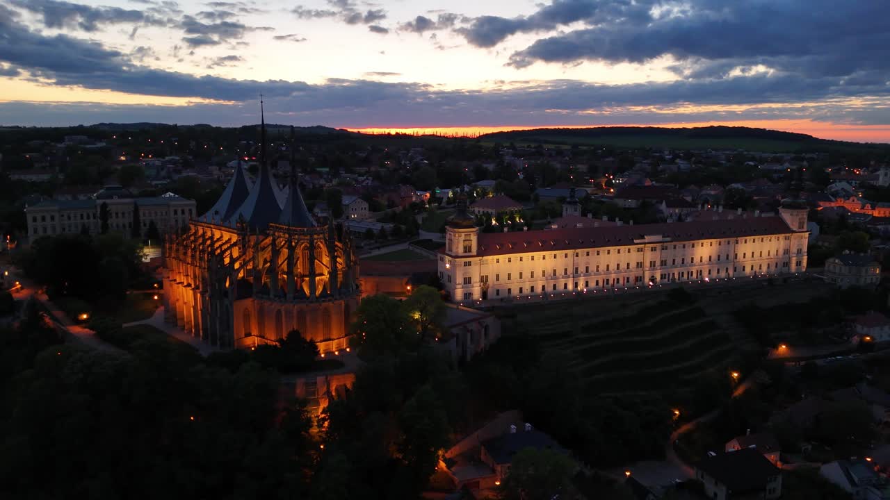 Evening view of Saint Barbara Cathedral in Kutna Hora glowing orange under moody sky