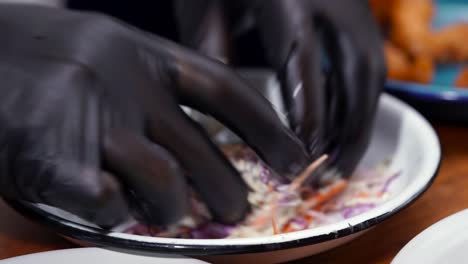 mexican chef wearing black gloves preparing cabbage salad for shrimp taco baja california style