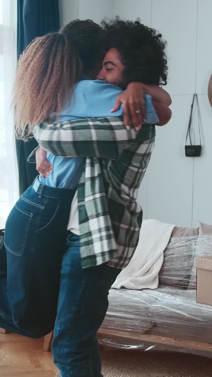 Young joy multinational man and woman hugging after arriving in new apartment
