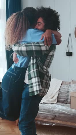 young joy multinational man and woman hugging after arriving in new apartment