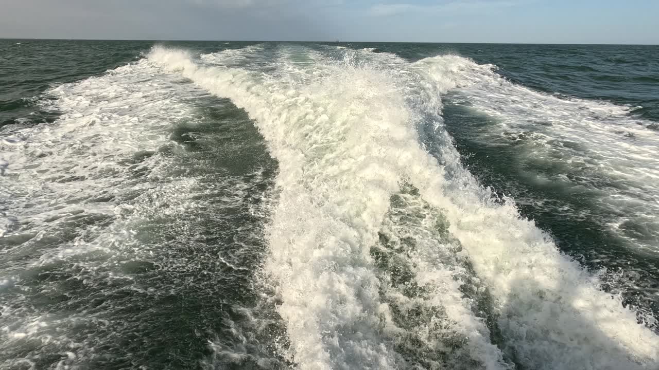 ⁇ 은 하늘의 날, 파란 바다, 물 표면에서 빠르게 움직이는 모터 보트의 뒤에서 볼 수 있는 물의 흔적