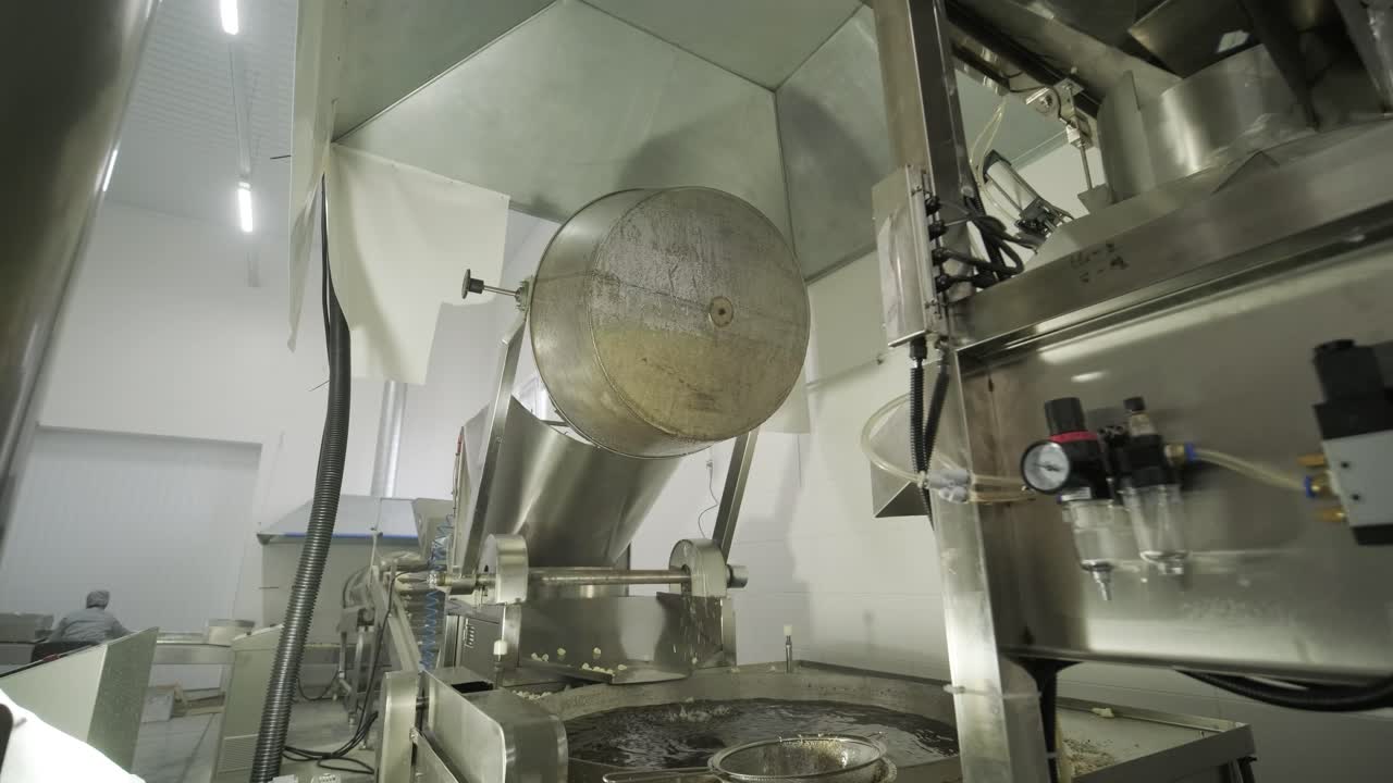 máquina de fritura industrial, las papas fritas se fríen en un cuenco grande con aceite.