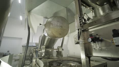 industrial deep frying machine, chips are fried in a large bowl with oil.