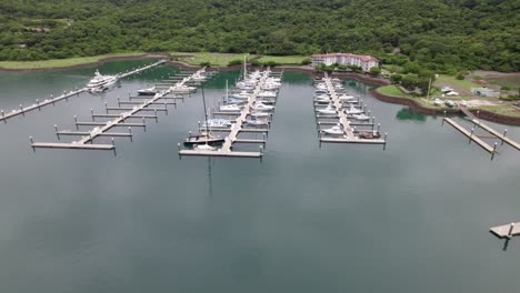 Aerial-truck-left-of-boats-parked-in-dock-near-hillside-coast-covered-in-forest,-Nacascolo-beach,-Papagayo-Peninsula,-Costa-Rica
