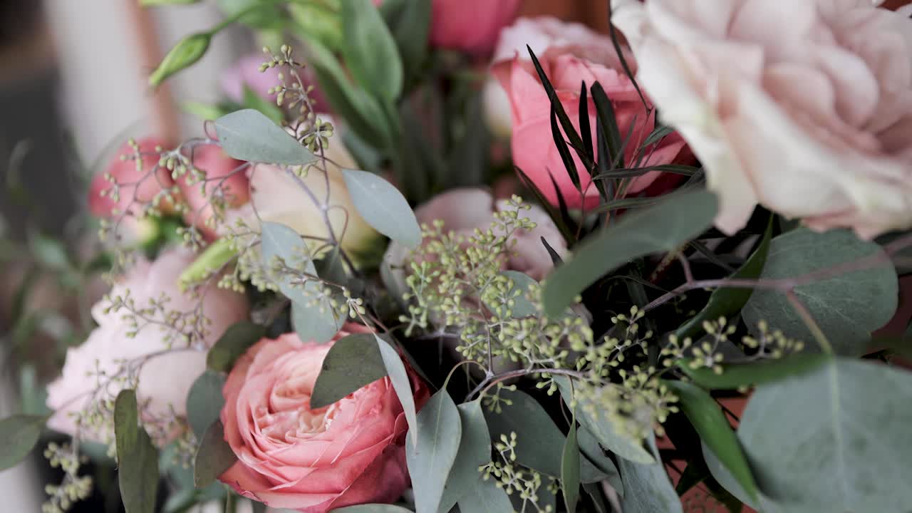 Gros plan d'un bouquet de fleurs de mariage roses et de verdure en extérieur, 1080p 60fps