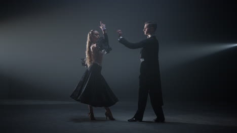 beautiful dancers performing on dark stage. ballroom couple dancing in hall.