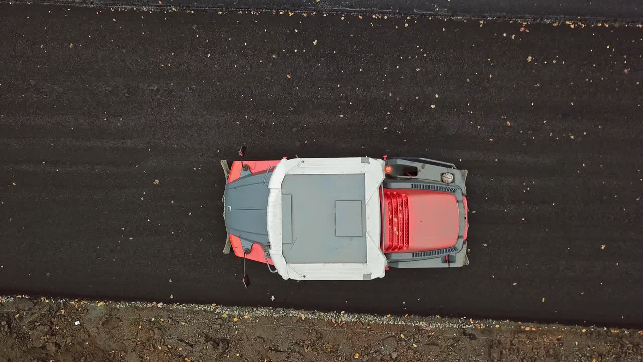 Aerial view of a truck at roadworks. Top view of asphalt compactor pressuring the new road outside. Slow motion.