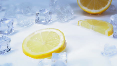 cámara lenta - toma de una sabrosa rodaja de limón girando sobre una mesa azul claro y blanca con cubitos de hielo