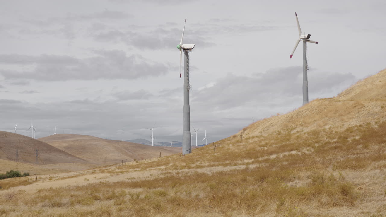Two windmills on dry hill in foreground