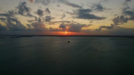 approach of small single island surrounded by water, dusk evening aerial