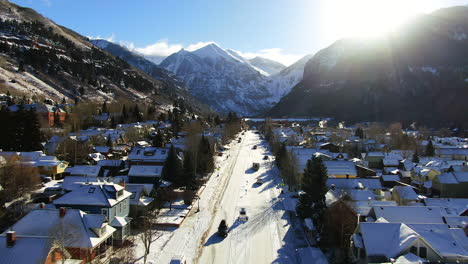 Aerial-Cinematic-Drone-view-of-Telluride-mountain-ski-resort-downtown-Colorado-of-scenic-mountains-landscape-and-historic-buildings-fresh-snow-trucks-and-car-early-sun-mid-winter-forward-movement