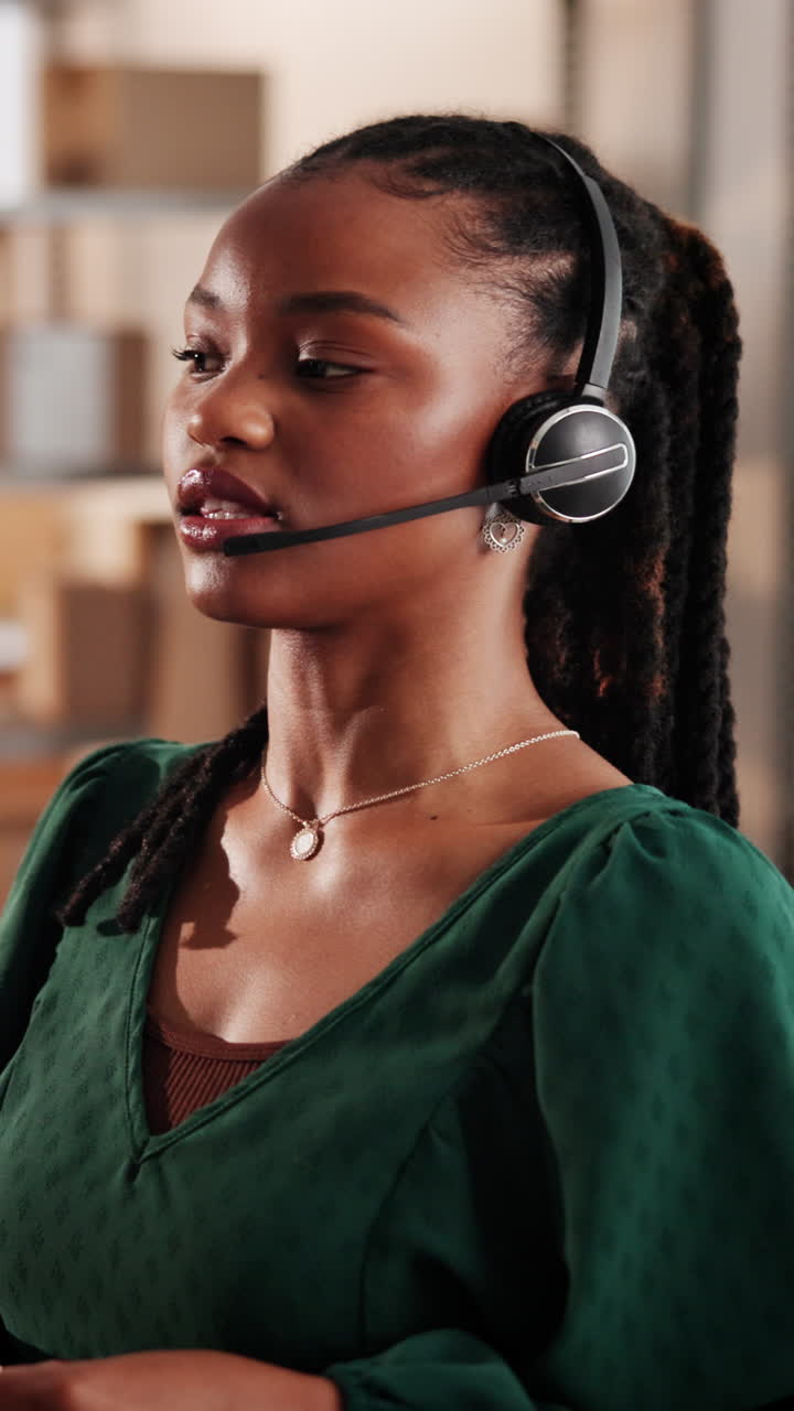 Ung svart kvinne med headset som snakker på et kundesenter