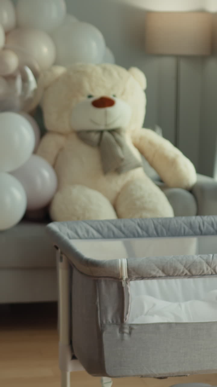 Allestimento accogliente della cameretta con una culla, un grande orsetto di peluche e palloncini, che creano un'atmosfera calda e accogliente.