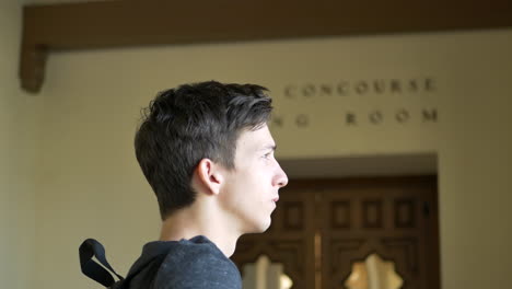 a young caucasian man traveling alone with a backpack waiting for his train to arrive at the station