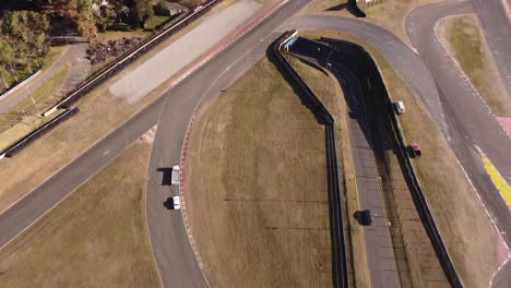 Una-Toma-Aérea-Dinámica-De-Un-Camión-Grande-Mientras-Remolca-Un-Auto-De-Carreras-Totalizado-A-Un-Lugar-Seguro