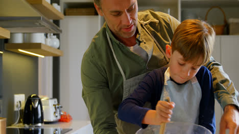 Vista-Frontal-De-Un-Padre-E-Hijo-Caucásicos-De-Mediana-Edad-Horneando-Galletas-En-La-Cocina-De-Una-Casa-Cómoda-4k