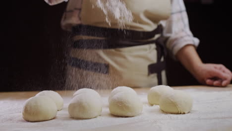 el panadero rocía harina sobre los pasteles sin hornear