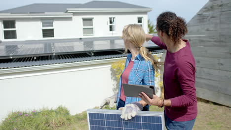 Busy-diverse-couple-using-tablet-and-holding-solar-panel-in-garden,-slow-motion