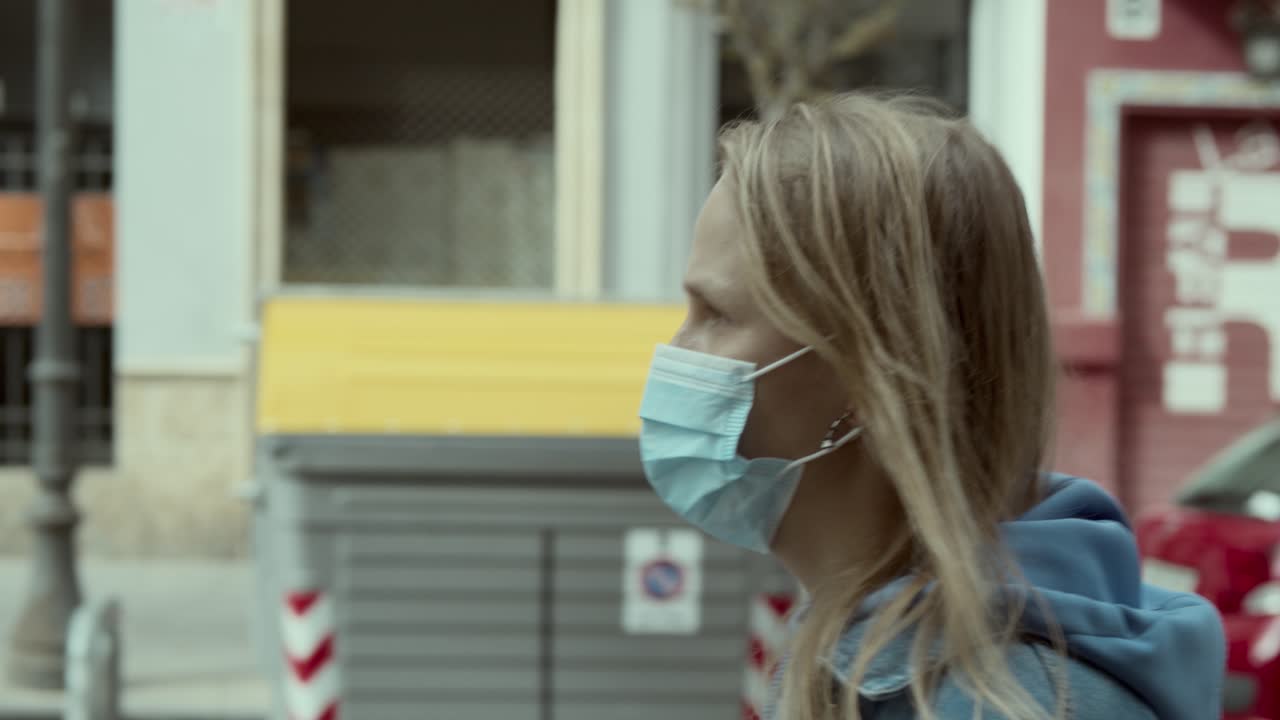 마스크를 입은 여자가 도시를 가로질러