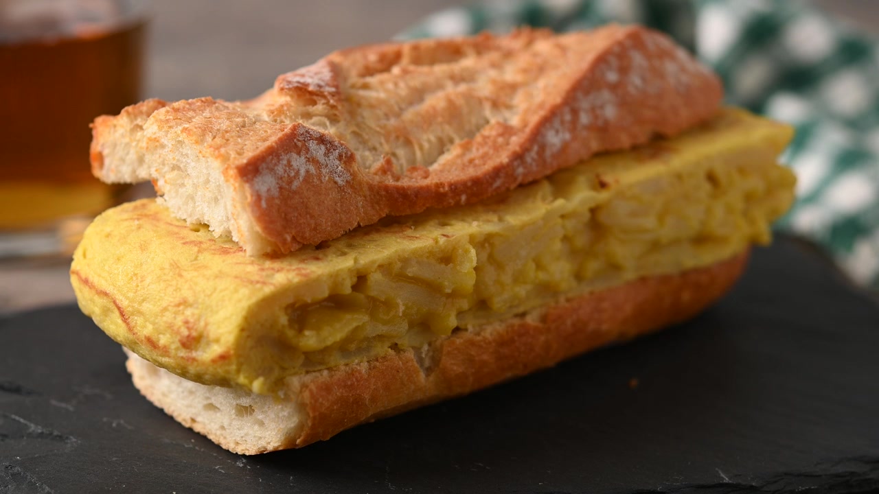 Panino con tortilla di patate spagnola su tavolo di legno. Bocadillo de tortilla