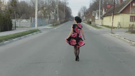 Una-Joven-Atractiva-Con-Un-Vestido-Con-Flores-Corriendo-Por-La-Carretera.