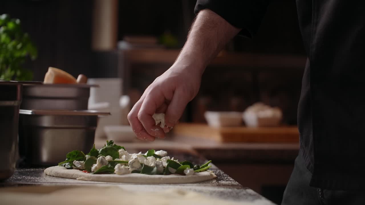 Chef preparing a pizza with blue cheese and spinach