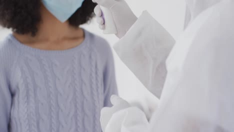 woman wearing face mask getting her temperature measured