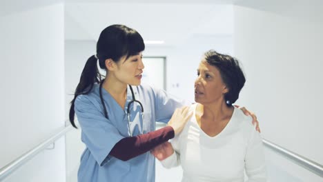 Joven-Médico-Ayudando-Al-Paciente-A-Caminar-En-El-Pasillo-Del-Hospital-4k