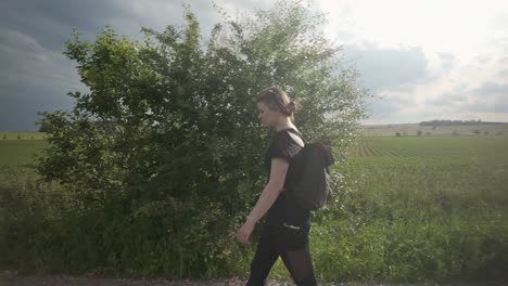 una chica con una mochila camina sola por campos soleados, disfrutando de los beneficios saludables de los viajes y el paisaje natural sereno