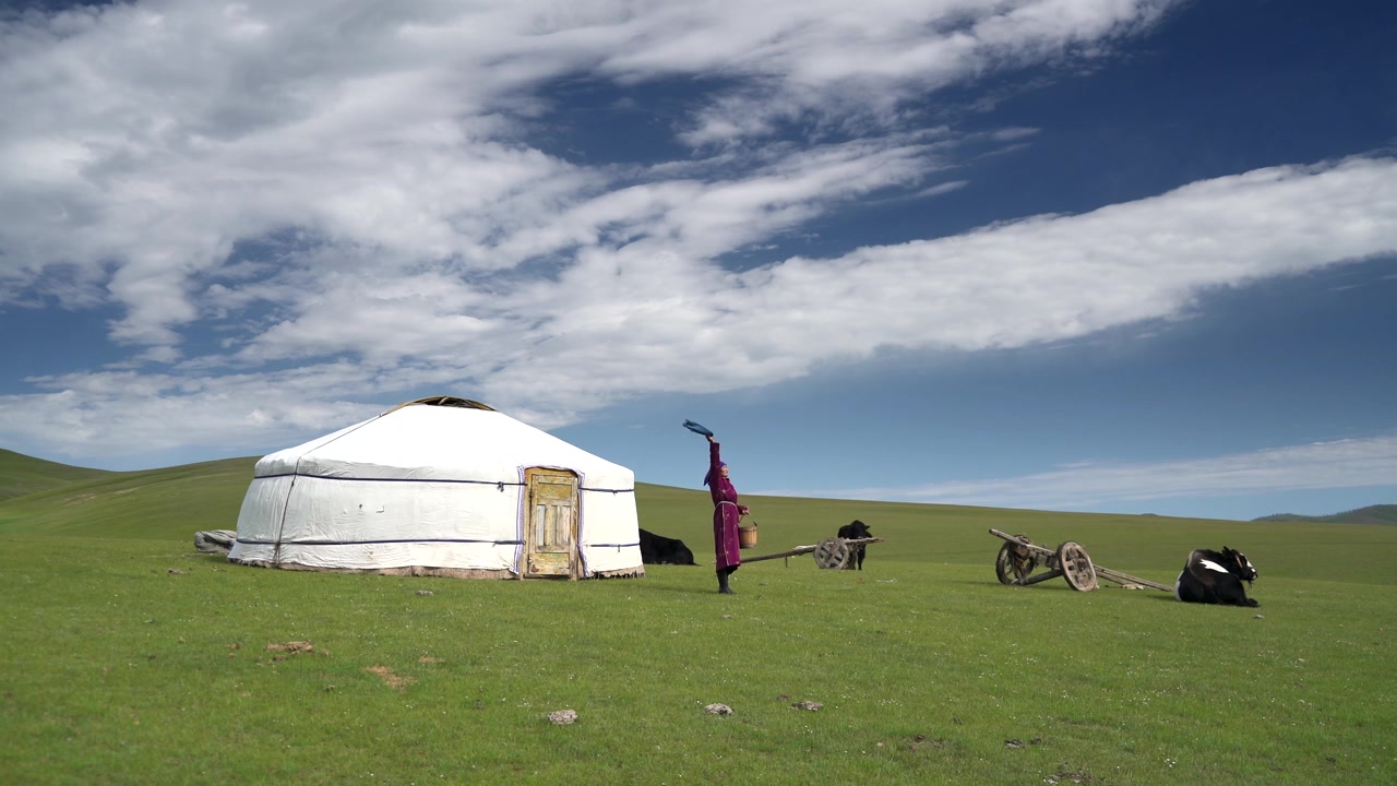 Mongolsk kvinde i traditionel beklædning stående udenfor en jurte