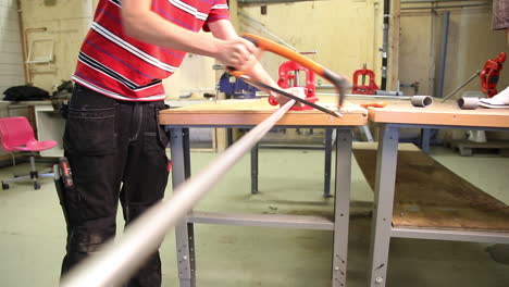 close up of a young male intern sawing an iron bar with a in a workshop