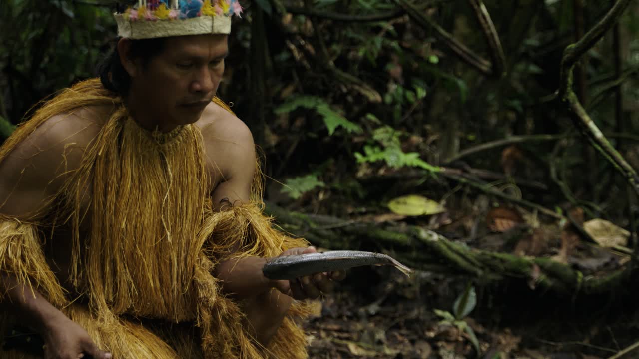 An indigenous man holds a fish that died due to environmental pollution in a dense forest in Leticia, Amazon, Colombia