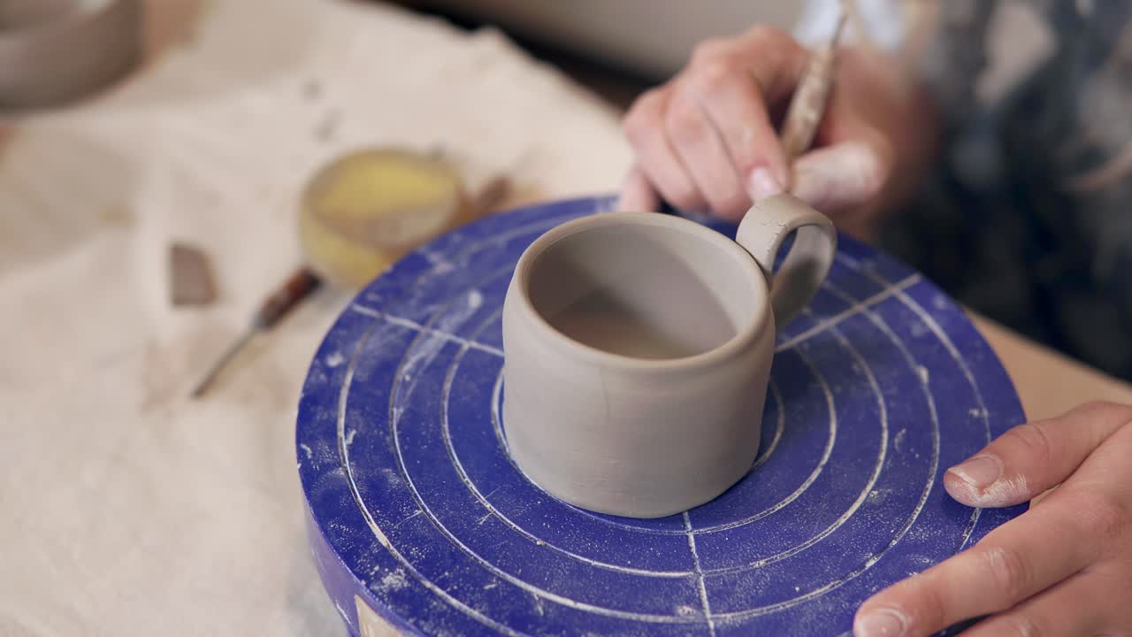 mujer haciendo una taza en una rueda de cerámica