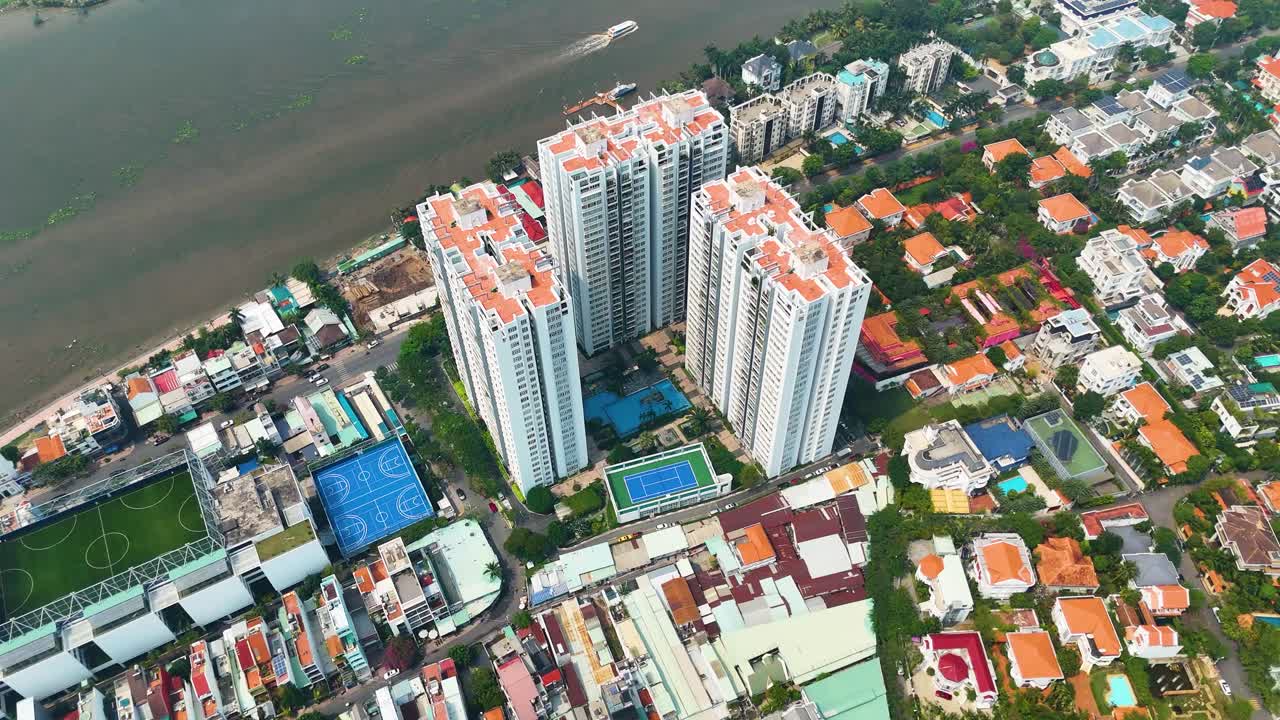 Aerial: condo apartments with sports courts during the day in Ho Chi Minh City, Vietnam, crane down drone shot