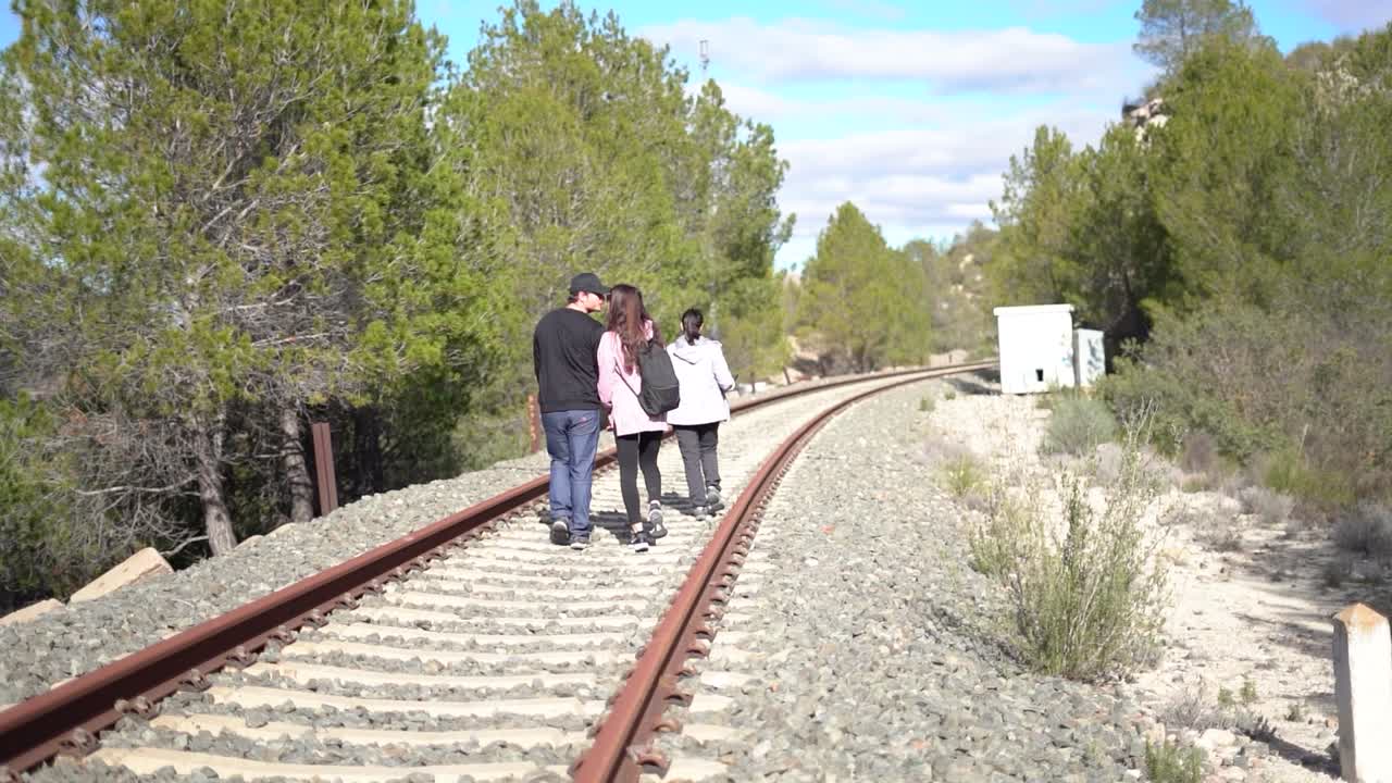 People walking on abandoned railway. Forgotten paths hiker group of backpacker friends. Hiking adventure in nature.