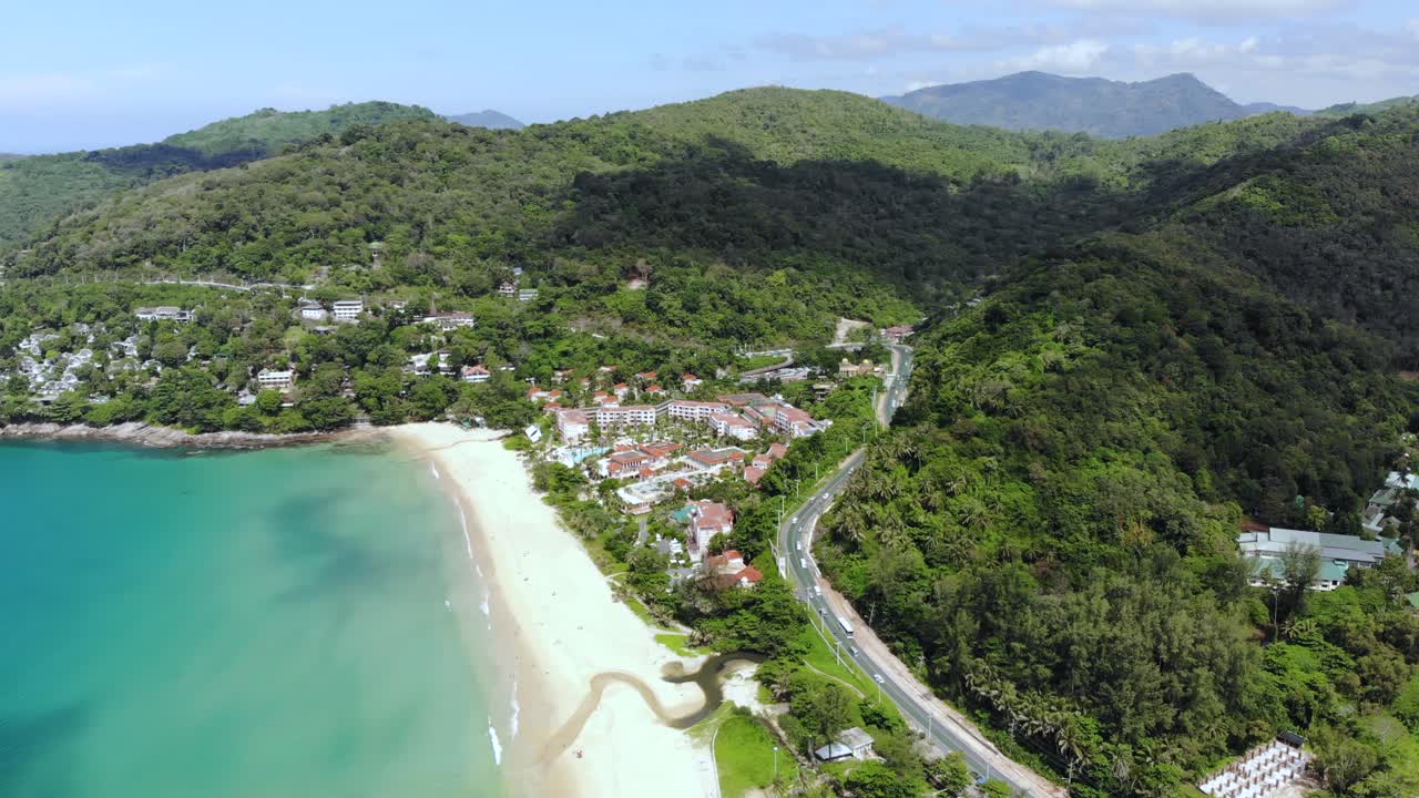 Winding road at tropical mountain by white sand Phuket beach. Aerial