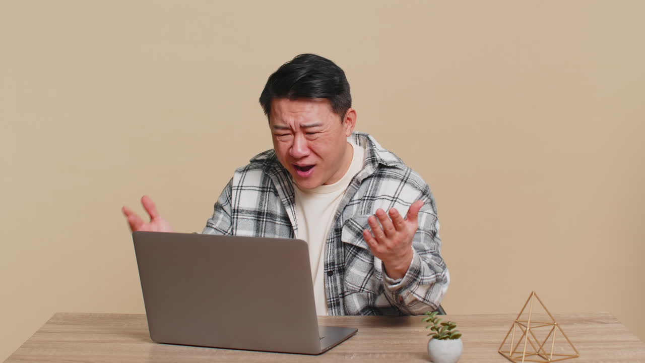 Man using laptop surprised by bad news fortune loss game fail lottery results sitting at table