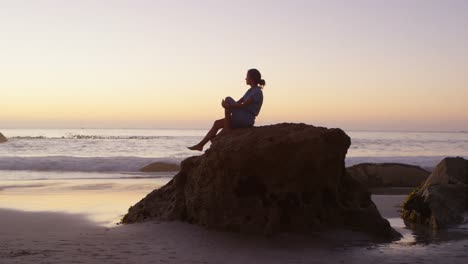mujer relajándose en una roca en la playa 4k