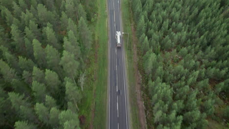 aerial bird view of forest road in finland, white oil truck passing by, traffic, summer, overcast day