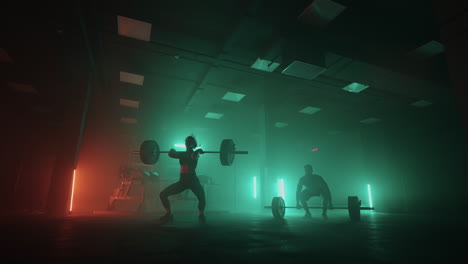 sporty man and woman are lifting weights in dark gym training together powerlifting show