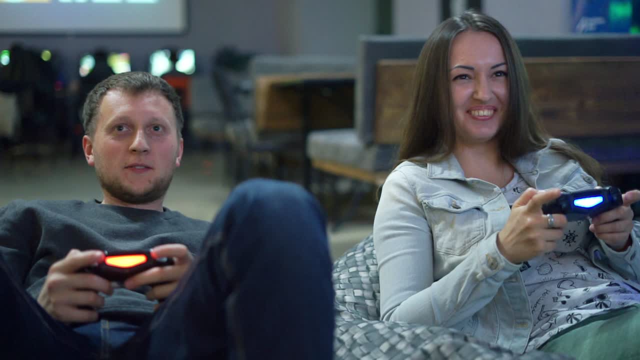 una pareja joven jugando un videojuego en casa. un hombre explicando cómo jugar y usar el controlador de juego. controlador de juego inalámbrico