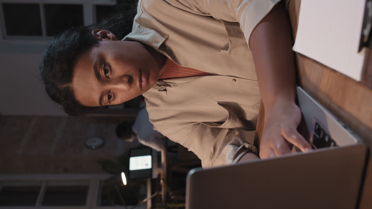 Woman Working on Laptop in a Dimly Lit Room