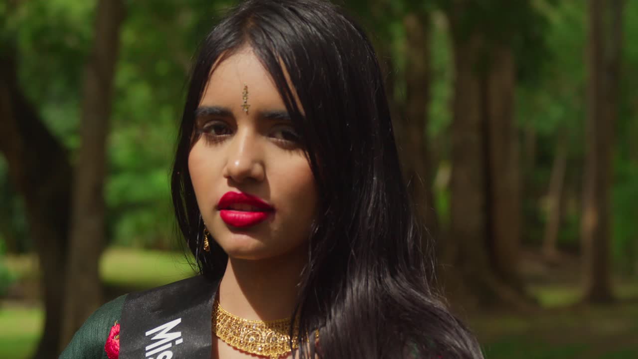 At a tropical park in the Caribbean, a young girl in traditional Indian attire enjoys her day.