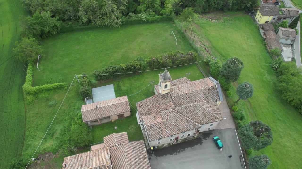Orbitowanie drona wokół romańskiego kościoła San Lorenzo Martire w wiejskiej wiosce San Lorenzo niedaleko Castell’Arquato we Włoszech. Średniowieczna architektura otoczona polami uprawnymi i okolicą